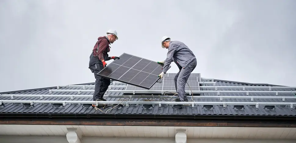 Zwei Arbeiter installieren Solarmodule auf dem Dach